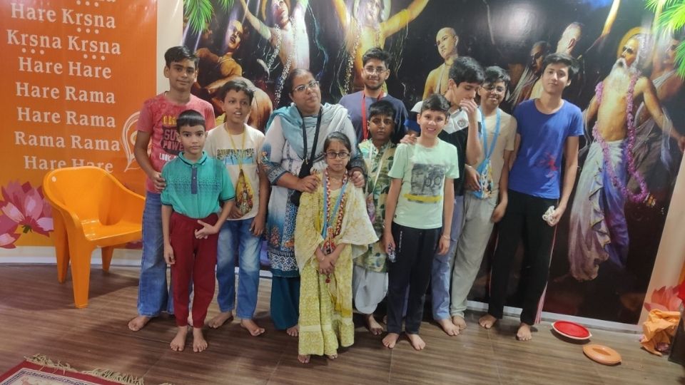 Students with their japa bead bags gathered with mentor in front of Pancha Tattva mural