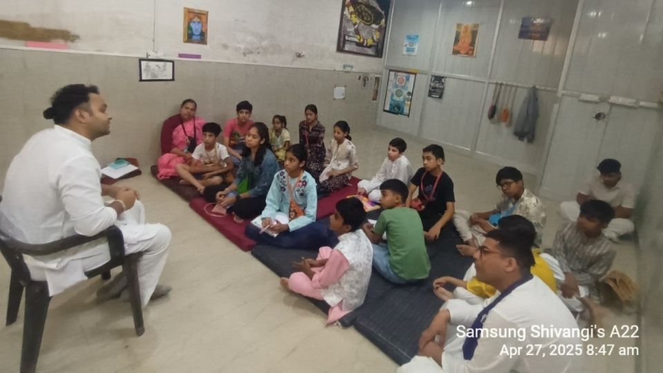 Devotee teacher seated with students on meditation mats during interactive morning class