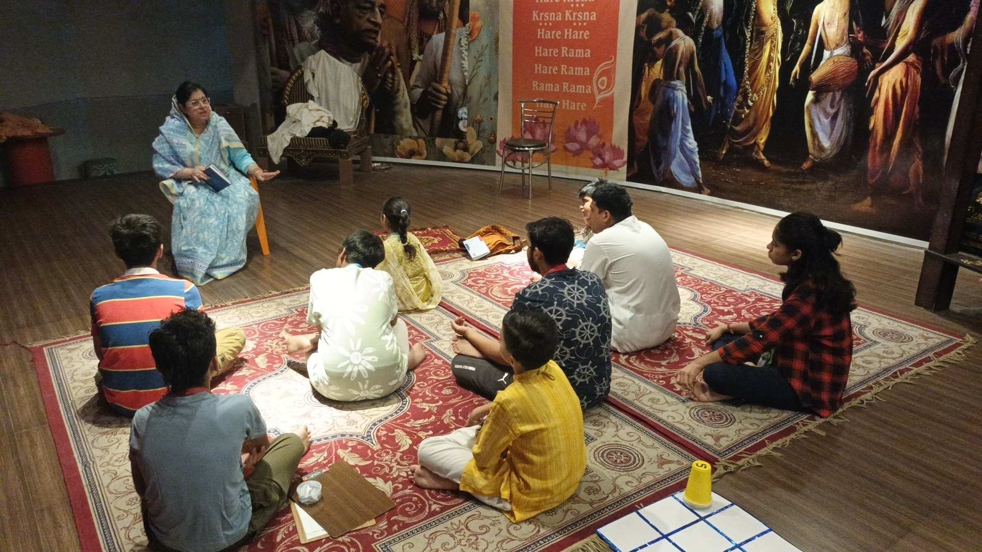 Senior Vaishnavi teacher conducting Vedic quiz and carpet games with children